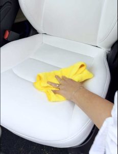 person using a cloth to Clean White Tesla Seats.